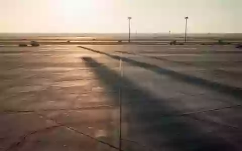 Leeres Rollfeld eines Flughafens während der Abenddämmerung mit langen Schatten auf dem Betonboden. - Foto: über boerse-global.de