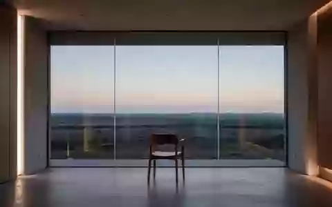 Ein minimalistischer, leerer Raum mit einem Stuhl vor einem großen Fenster, das auf eine weite Landschaft blickt. - Foto: über boerse-global.de