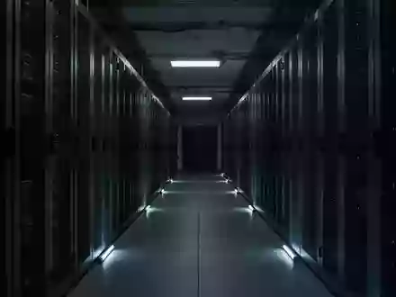 Dunkler Korridor mit Server-Racks in einem Rechenzentrum, beleuchtet durch dezentes Notlicht. - Foto: über boerse-global.de