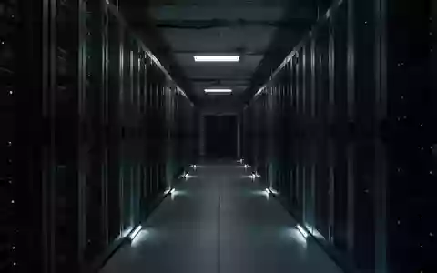 Dunkler Korridor mit Server-Racks in einem Rechenzentrum, beleuchtet durch dezentes Notlicht. - Foto: über boerse-global.de
