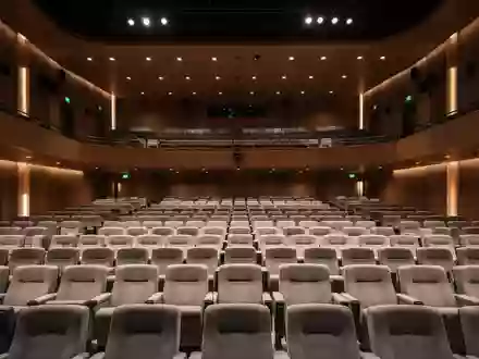 Ein moderner, leerer Theatersaal mit ordentlichen Sitzreihen in einer ruhigen, atmosphärischen Beleuchtung. - Foto: über boerse-global.de