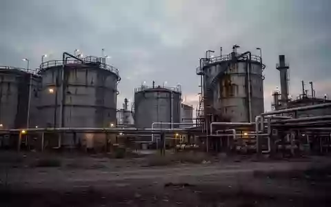 Industrielle Raffinerieanlage mit großen Stahltanks und Rohrleitungen bei Dämmerung. - Foto: über boerse-global.de