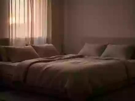 Ein ruhig gestaltetes Schlafzimmer mit sanftem Morgenlicht, das auf ein unbenutztes, ordentlich gemachtes Bett fällt. - Foto: über boerse-global.de