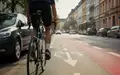 Ein Fahrradfahrer hält auf einer städtischen Straße in Bonn den Sicherheitsabstand zu parkenden Autos ein. - Foto: über boerse-global.de