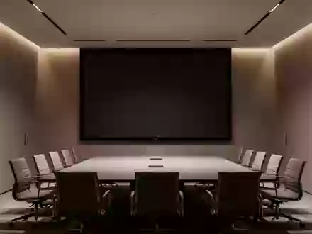 Ein leerer, modern gestalteter Konferenzraum mit einer großen, dunklen Projektionsfläche und dezenter Beleuchtung. - Foto: über boerse-global.de