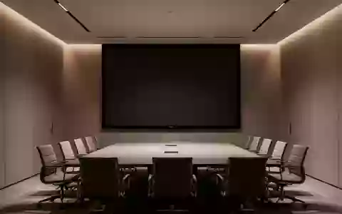 Ein leerer, modern gestalteter Konferenzraum mit einer großen, dunklen Projektionsfläche und dezenter Beleuchtung. - Foto: über boerse-global.de