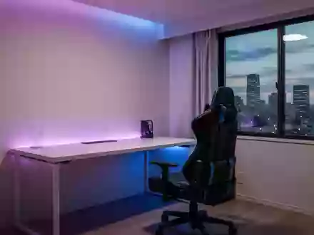 Ein minimalistisch eingerichteter Gaming-Raum mit stimmungsvoller Beleuchtung und Blick auf eine japanische Stadt bei Dämmerung. - Foto: über boerse-global.de