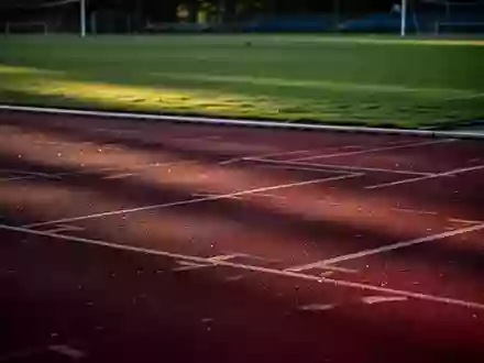 Eine leere Sportanlage bei Dämmerung mit einer roten Laufbahn und einem grünen Rasenplatz. - Foto: über boerse-global.de