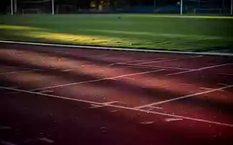 Eine leere Sportanlage bei Dämmerung mit einer roten Laufbahn und einem grünen Rasenplatz. - Foto: über boerse-global.de