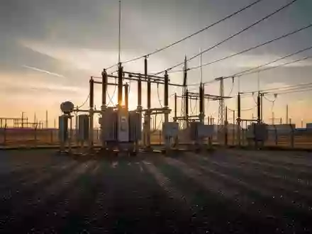 Ein Hochspannungstransformator in einem weitläufigen Industriegelände bei Sonnenuntergang. - Foto: über boerse-global.de
