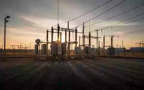 Ein Hochspannungstransformator in einem weitläufigen Industriegelände bei Sonnenuntergang. - Foto: über boerse-global.de