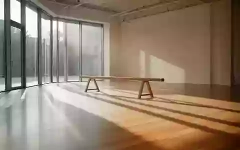 Ein minimalistisch gestalteter Fitnessraum mit hellem Holzboden und einfallendem Sonnenlicht, der eine ruhige Atmosphäre zur Körperausrichtung vermittelt. - Foto: über boerse-global.de