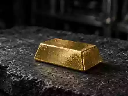 Ein einzelner Goldbarren auf einer dunklen Schieferplatte in einem schwach beleuchteten Tresor. - Foto: über boerse-global.de