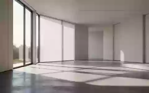 Ein minimalistischer, moderner Innenraum mit natürlichem Lichteinfall und klaren geometrischen Schatten auf einem Betonboden. - Foto: über boerse-global.de