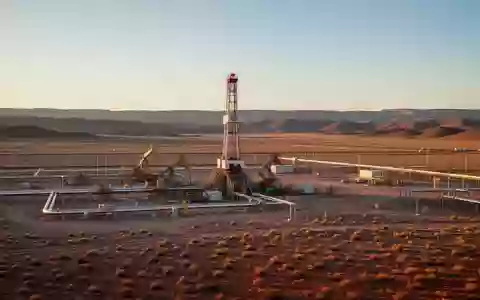 Industrielle Bohranlage in einer weiten Beckenlandschaft bei Sonnenuntergang. - Foto: über boerse-global.de