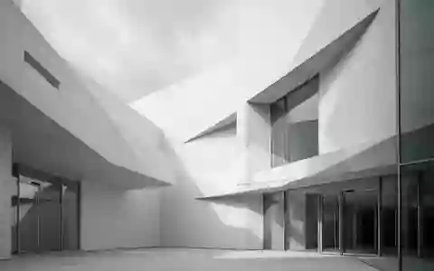 Moderne, minimalistische Fassade eines Verwaltungsgebäudes mit geometrischen Schattenwürfen bei bewölktem Tageslicht. - Foto: über boerse-global.de