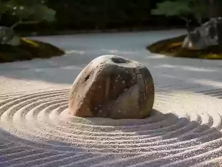 Ein minimalistischer Zen-Garten mit geharktem Sand und einem glatten Stein als Symbol für Ruhe und bewusste Atmung. - Foto: über boerse-global.de