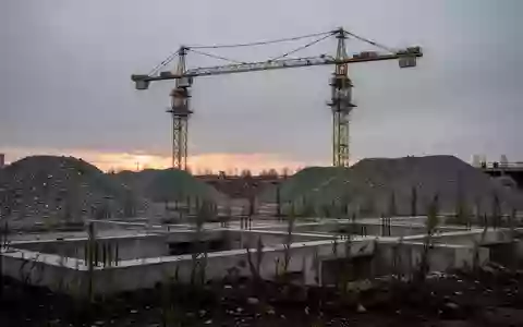 Eine verlassene Baustelle mit einem unbewegten Baukran und Betonfundamenten bei Dämmerung. - Foto: über boerse-global.de