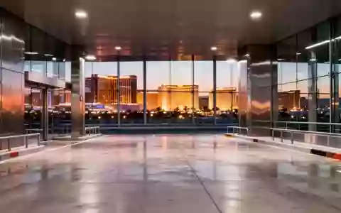 Eine menschenleere, moderne Abholzone in einem Flughafen bei Dämmerung mit Blick auf die Lichter der Stadt Las Vegas. - Foto: über boerse-global.de