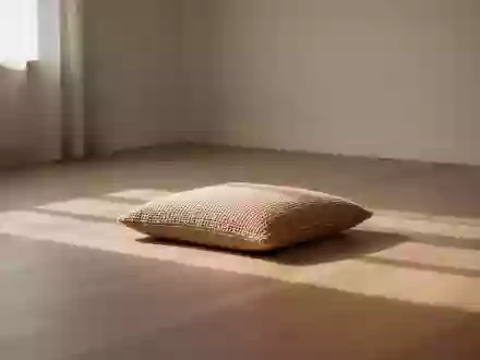 Ein minimalistischer, ruhiger Raum mit weichem Tageslicht, einem einzelnen Sitzkissen und einer klaren, entspannten Atmosphäre. - Foto: über boerse-global.de