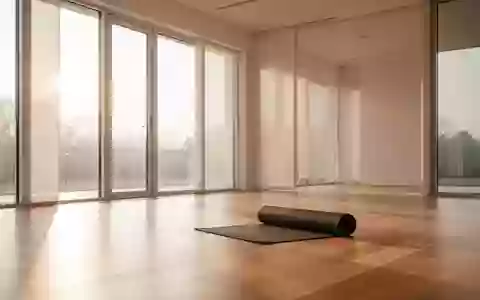 Ein minimalistischer, lichtdurchfluteter Übungsraum mit Holzboden und einer zusammengerollten Yogamatte. - Foto: über boerse-global.de
