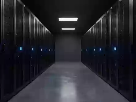 Ein minimalistischer, dunkel beleuchteter Serverraum mit metallischen Schaltschränken und blauen Statusleuchten. - Foto: über boerse-global.de