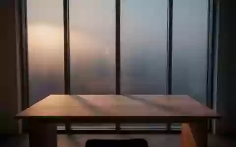 Ein minimalistischer, ruhiger Arbeitsplatz mit einem leeren Holztisch vor einem Fenster, das sanftes Tageslicht einlässt. - Foto: über boerse-global.de