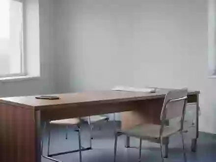 Ein minimalistisches, unbesetztes Arztzimmer mit einem Schreibtisch und einem Stuhl bei natürlichem Tageslicht. - Foto: über boerse-global.de