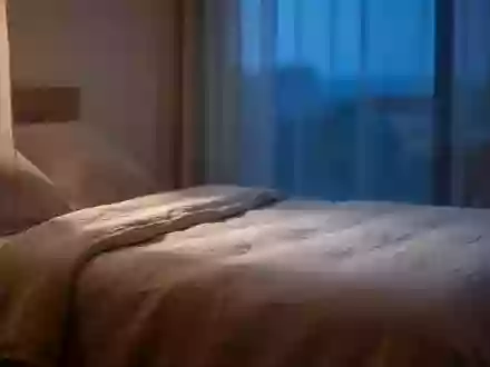 Ein minimalistisch eingerichtetes Schlafzimmer in den frühen Morgenstunden mit natürlichem, sanftem Licht. - Foto: über boerse-global.de