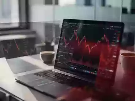 Ein moderner Schreibtisch mit einem Laptop, auf dem ein fallender Aktienkurs zu sehen ist, in einem Büro. - Foto: über boerse-global.de