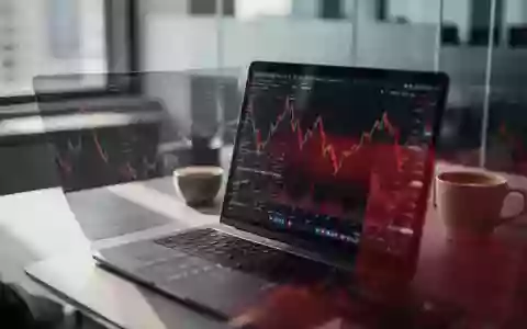 Ein moderner Schreibtisch mit einem Laptop, auf dem ein fallender Aktienkurs zu sehen ist, in einem Büro. - Foto: über boerse-global.de