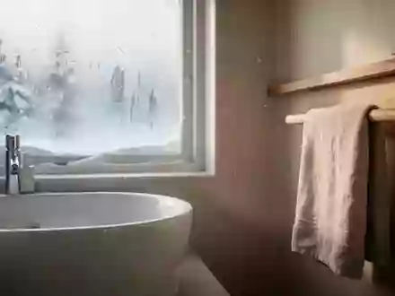 Ein minimalistisches, lichtdurchflutetes Badezimmer im Winter mit einem gefrosteten Fenster und einem weißen Keramikwaschbecken. - Foto: über boerse-global.de