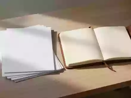 Ein sauberer Schreibtisch mit einem Stapel weißem Papier und einem leeren Notizbuch in natürlichem Licht. - Foto: über boerse-global.de