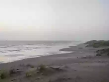 Eine ruhige, weitläufige Nordseeküste mit Dünen und flachem Wasser bei Dämmerung, die eine Atmosphäre der Stille vermittelt. - Foto: über boerse-global.de