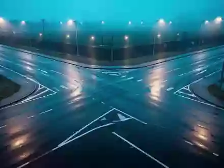 Eine leere Straßenkreuzung bei Dämmerung mit Reflexionen von kühlem Licht auf nassem Asphalt. - Foto: über boerse-global.de