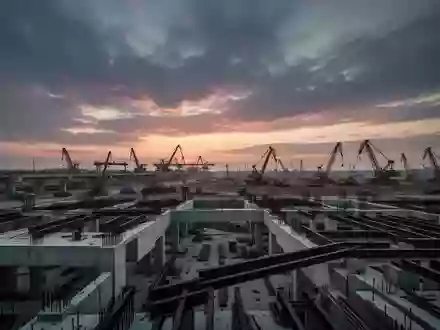 Eine weitläufige Baustelle für großflächige Infrastrukturprojekte bei Dämmerung mit massiven Betonfundamenten und Stahlträgern. - Foto: über boerse-global.de
