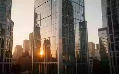 Moderne Glasfassade eines Bürogebäudes in einer urbanen Umgebung bei Sonnenuntergang. - Foto: über boerse-global.de