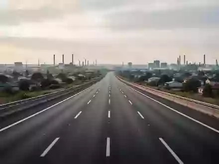 Eine leere, moderne Autobahn führt bei bedecktem Himmel in Richtung eines urbanen Horizonts. - Foto: über boerse-global.de
