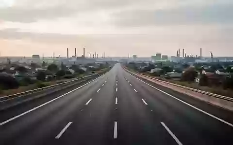 Eine leere, moderne Autobahn führt bei bedecktem Himmel in Richtung eines urbanen Horizonts. - Foto: über boerse-global.de