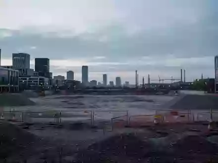Eine weitläufige, unbebaute städtische Brachfläche in Wolfsburg bei Dämmerung, im Hintergrund sind moderne Stadtstrukturen zu sehen. - Foto: über boerse-global.de