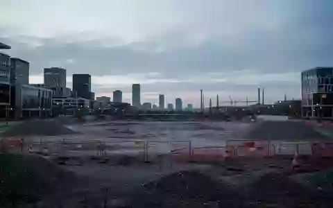 Eine weitläufige, unbebaute städtische Brachfläche in Wolfsburg bei Dämmerung, im Hintergrund sind moderne Stadtstrukturen zu sehen. - Foto: über boerse-global.de