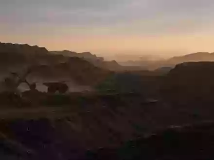 Große Tagebau-Mine bei Sonnenaufgang mit schweren Maschinen in einer weitläufigen Erdausgrabung. - Foto: über boerse-global.de