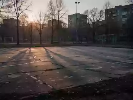 Ein verlassener, leerer Sportplatz bei Dämmerung mit langen Schatten auf dem Betonboden. - Foto: über boerse-global.de