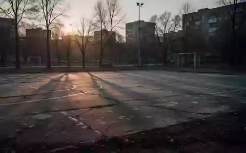 Ein verlassener, leerer Sportplatz bei Dämmerung mit langen Schatten auf dem Betonboden. - Foto: über boerse-global.de