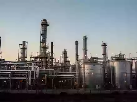 Industrielle Raffinerieanlage mit Stahlrohren und Speichertanks bei Dämmerung. - Foto: über boerse-global.de
