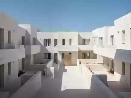 Leerer Innenhof eines mediterranen Wohnkomplexes mit weißer Architektur und klaren Linien unter blauem Himmel. - Foto: über boerse-global.de