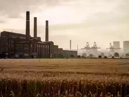 Weitläufige Industrielandschaft mit Fabrikgebäuden und Schornsteinen vor einem bewölkten Himmel. - Foto: über boerse-global.de