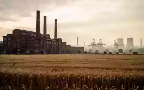 Weitläufige Industrielandschaft mit Fabrikgebäuden und Schornsteinen vor einem bewölkten Himmel. - Foto: über boerse-global.de