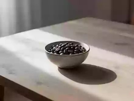 Nahaufnahme von gerösteten Kaffeebohnen in einer schlichten Keramikschale auf einem Holztisch bei natürlichem Licht. - Foto: über boerse-global.de