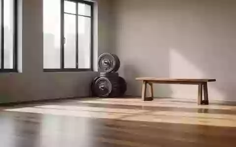 Ein heller, minimalistischer Fitnessraum mit Hantelscheiben und einer Holzbank in natürlichem Morgenlicht. - Foto: über boerse-global.de